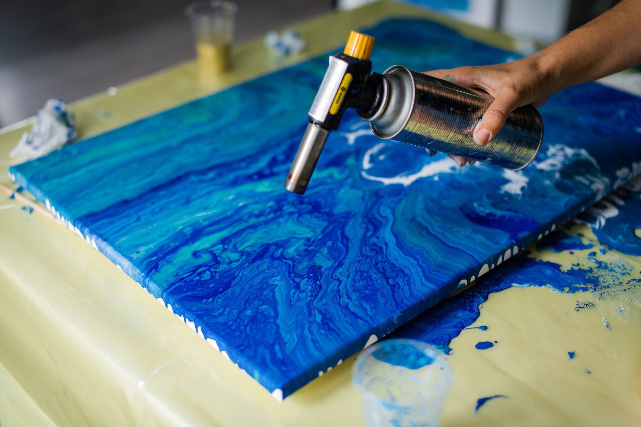 Artist creating blue resin art with a heat gun